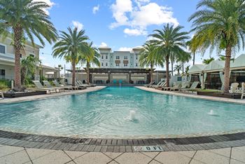A pool surrounded by palm trees and lounge chairs.